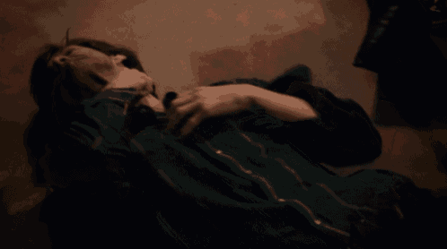 a man in a green shirt is laying on the floor with his hand on his chest