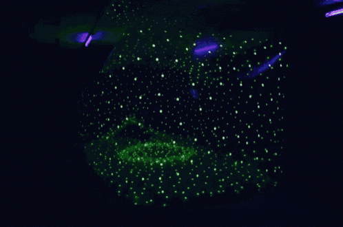 a green glowing object in the dark with purple lights in the background
