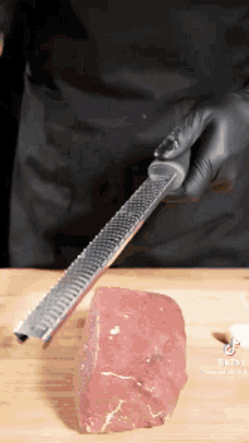 a person grating a piece of meat with a grater