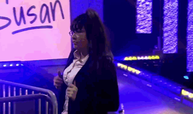 a woman stands in front of a sign that says " susan "