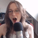 a woman is singing into a microphone with her mouth open .