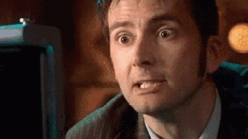 a man in a suit and tie is making a surprised face while looking at the camera .