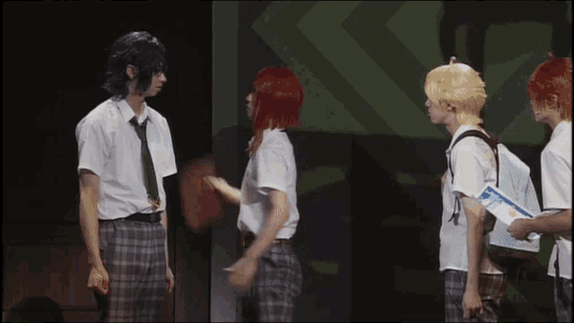 a group of people are standing on a stage and one of them is wearing a red wig