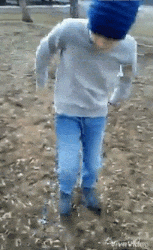 a person wearing a blue hat and a gray sweater is dancing in the dirt