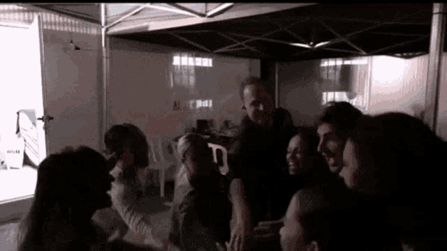 a group of people are gathered under a tent and one of them is wearing a black shirt that says ' a '