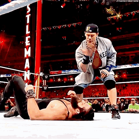 two men are wrestling in a wrestling ring and one is wearing a new york yankees shirt .