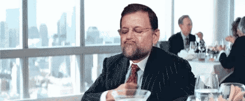 a man in a suit and tie is sitting at a table with a bowl of food in front of him .