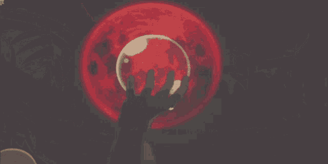a person holding a sphere in front of a red full moon