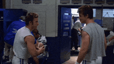 two football players standing in a locker room with a sign that says " return a champions "