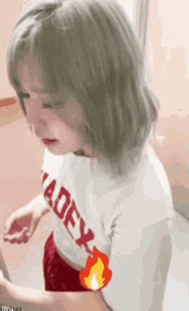 a girl with blonde hair is wearing a white t-shirt with the word adex on it and red shorts .