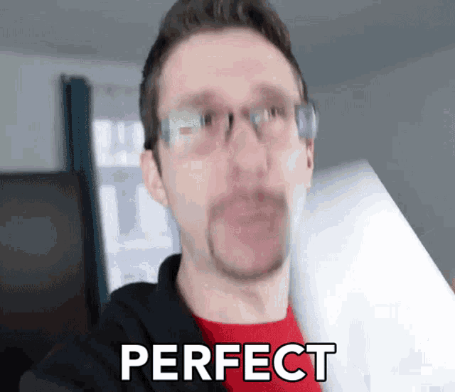 a man wearing glasses and a red shirt is holding a piece of paper and says perfect