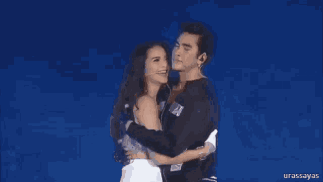 a man and a woman are hugging each other on stage .