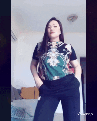 a woman in a floral shirt is dancing in a living room