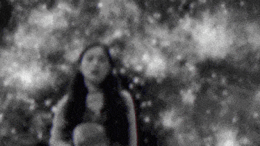 a black and white photo of a woman standing in the woods .
