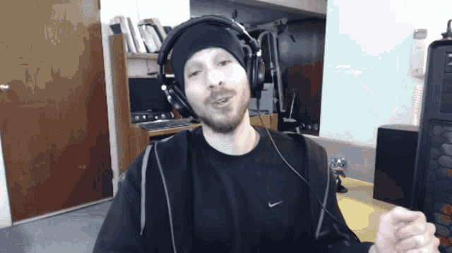 a man wearing headphones and a black nike shirt looks at the camera