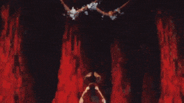 a person is standing in front of a large fireball in a dark room .