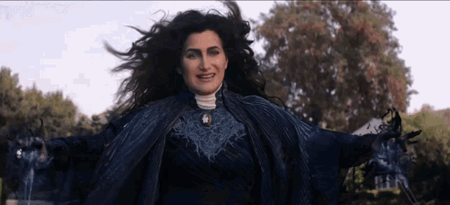 a woman with long hair is wearing a blue coat and a white shirt .