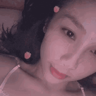 a close up of a woman 's face with a strawberry on her forehead .