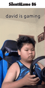 a boy in a blue tank top is holding a steering wheel while playing a video game ..