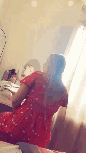a woman in a red dress is looking at herself in the mirror