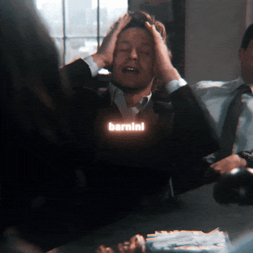 a man with his hands on his head has the word barnini glowing in the dark