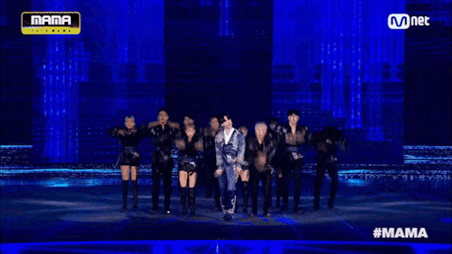 a group of people dancing on a stage with a mnet logo above them