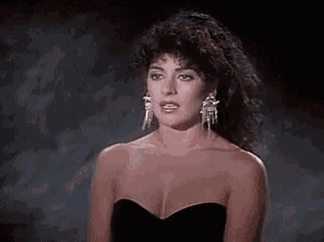 a woman in a black strapless dress and earrings is looking at the camera .