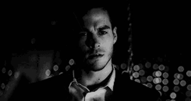 a man in a suit and tie is standing in front of a blurred background .