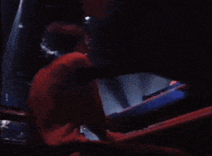a person playing a piano in a dark room with lights behind them