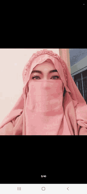 a woman wearing a pink hijab and covering her face with a pink veil
