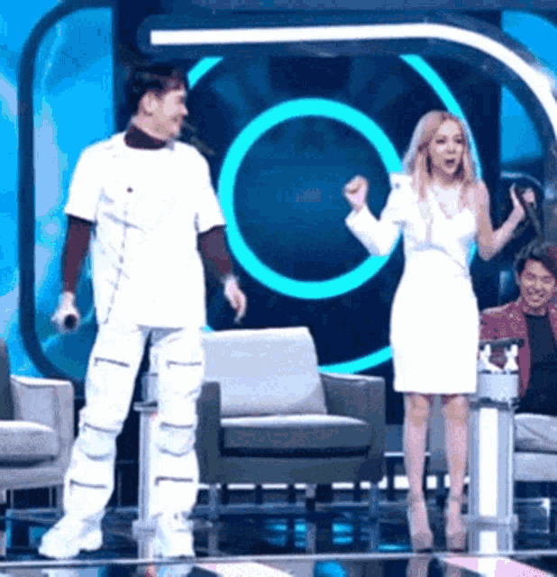 a woman in a white dress is standing next to a man in a white outfit