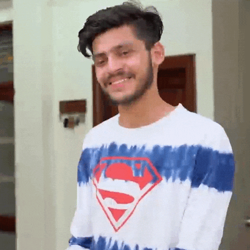 a man wearing a superman shirt is smiling and looking at the camera