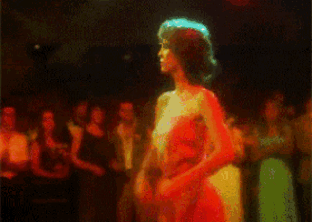 a woman in a red dress is dancing in a crowd