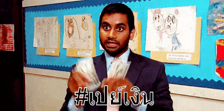 a man in a suit and tie is holding a bunch of money in front of a blue wall with drawings on it .