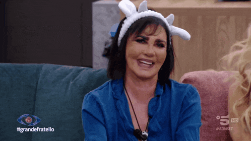 a woman sitting on a couch with a headband on her head and the words grandefratello on the bottom