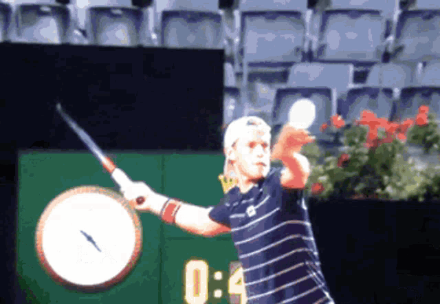 a tennis player is swinging a tennis racket in front of a clock that says 0:04