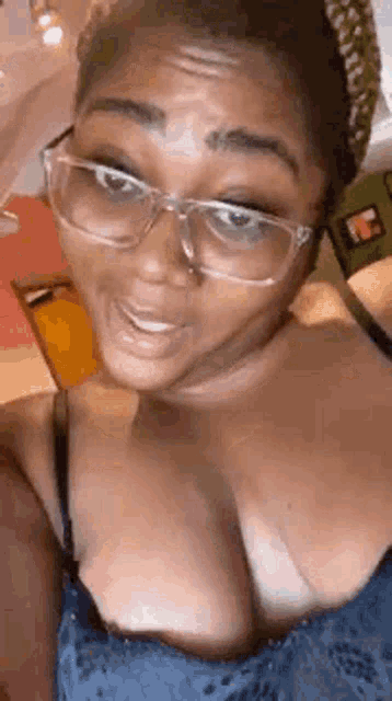 a woman wearing glasses and a bra is taking a selfie .