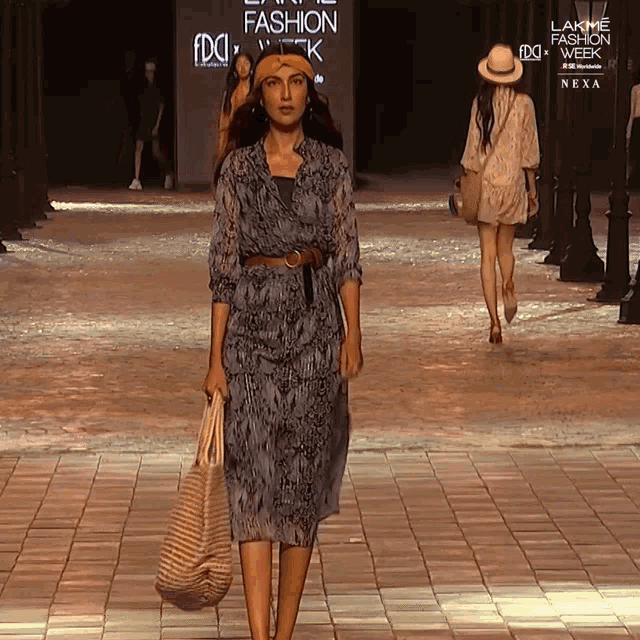 a woman walks down a runway at a fashion show