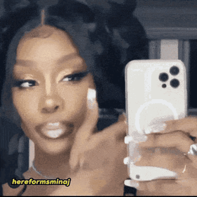 a woman is taking a picture of herself with her phone and the caption hereformsminaj