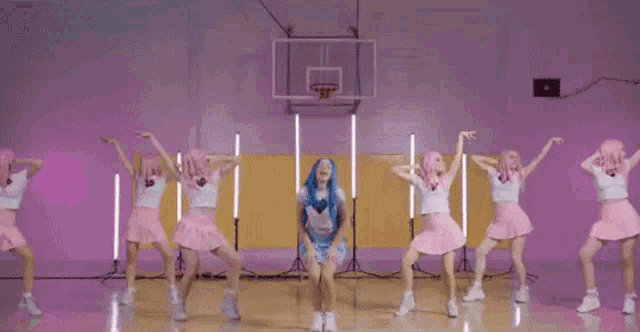 a group of girls are dancing in front of a basketball hoop .