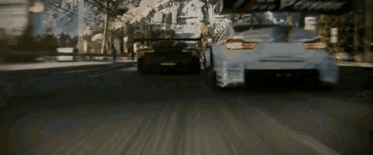 two cars are driving down a street and one of them has a sticker on the back that says ' r ' on it