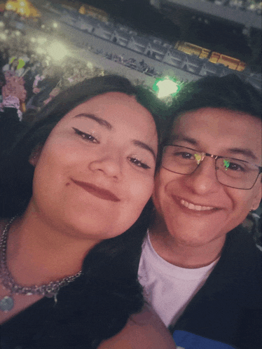 a man and a woman are posing for a picture in a stadium
