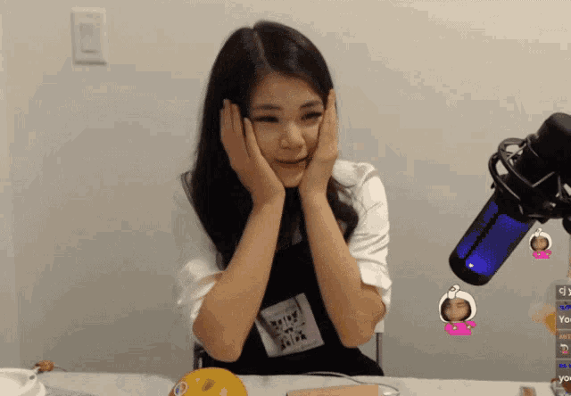 a woman sitting at a table with her hands on her face in front of a microphone that says you