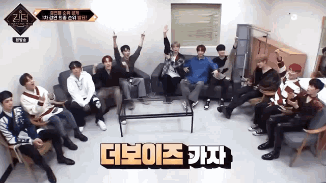 a group of young men are sitting in a living room with a sign that says ' 더보이즈 가자 ' on it