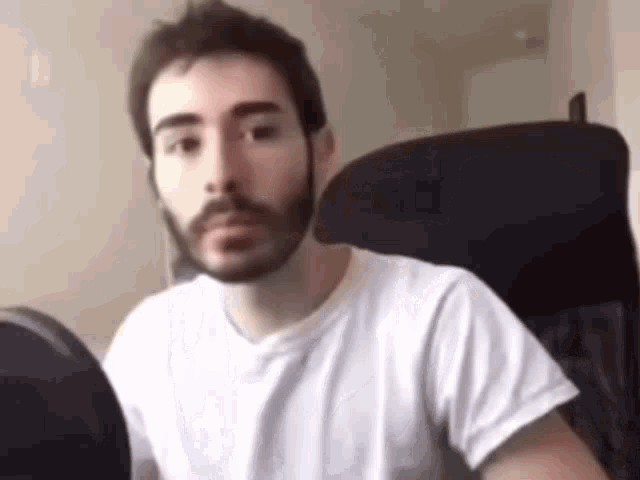 a man with a beard is sitting in a chair .