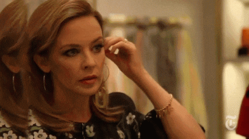 a woman is looking at herself in a mirror while wearing hoop earrings .