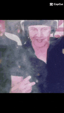 a man wearing headphones and a hat is giving a peace sign