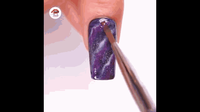 a person is painting a galaxy design on their nails with a brush