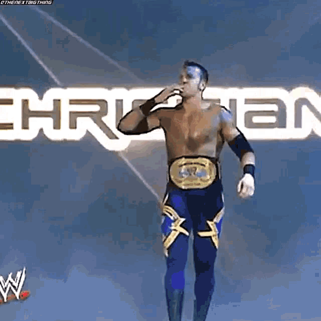 a wrestler is standing on a stage with a wrestling belt around his waist .