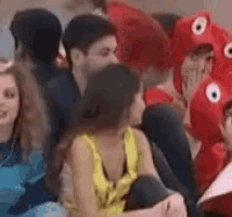 a group of people are sitting on a couch and one of them is wearing a red octopus hat .